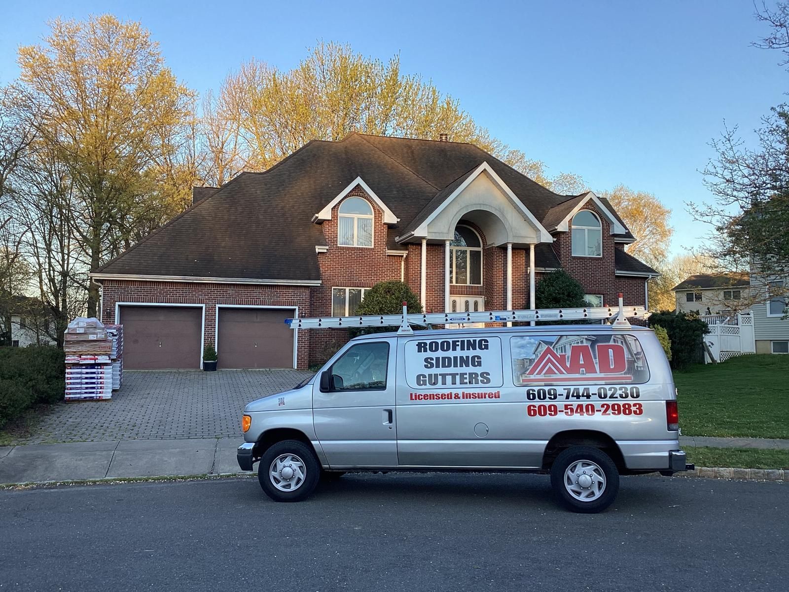 A Van Is Parked in Front of a Brick House — Burlington, NJ — AD Roofer Siding & Gutters