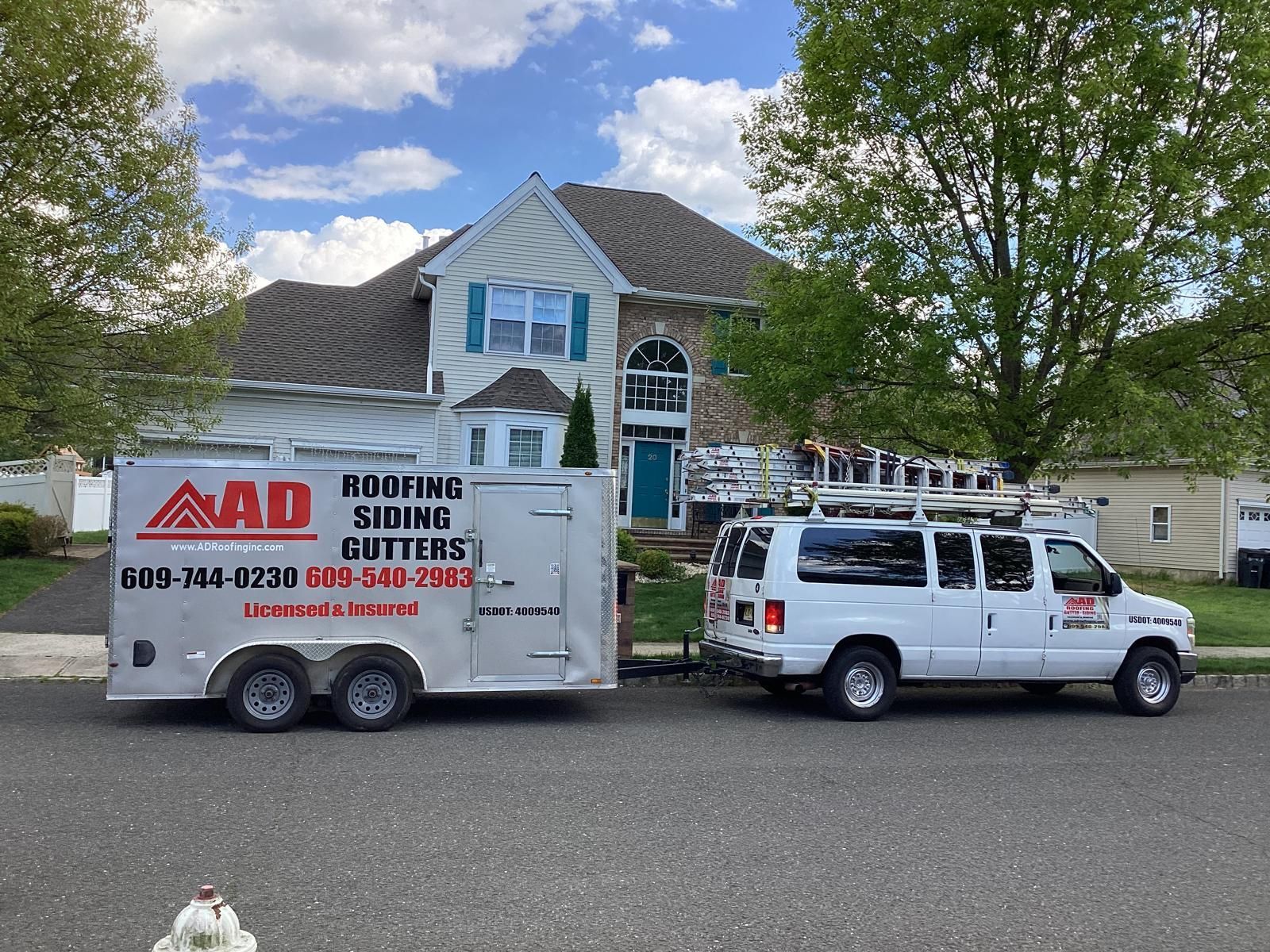 A White Van Is Parked Next to a Trailer That Says Roofing Siding Cutters — Burlington, NJ — AD Roofer Siding & Gutters
