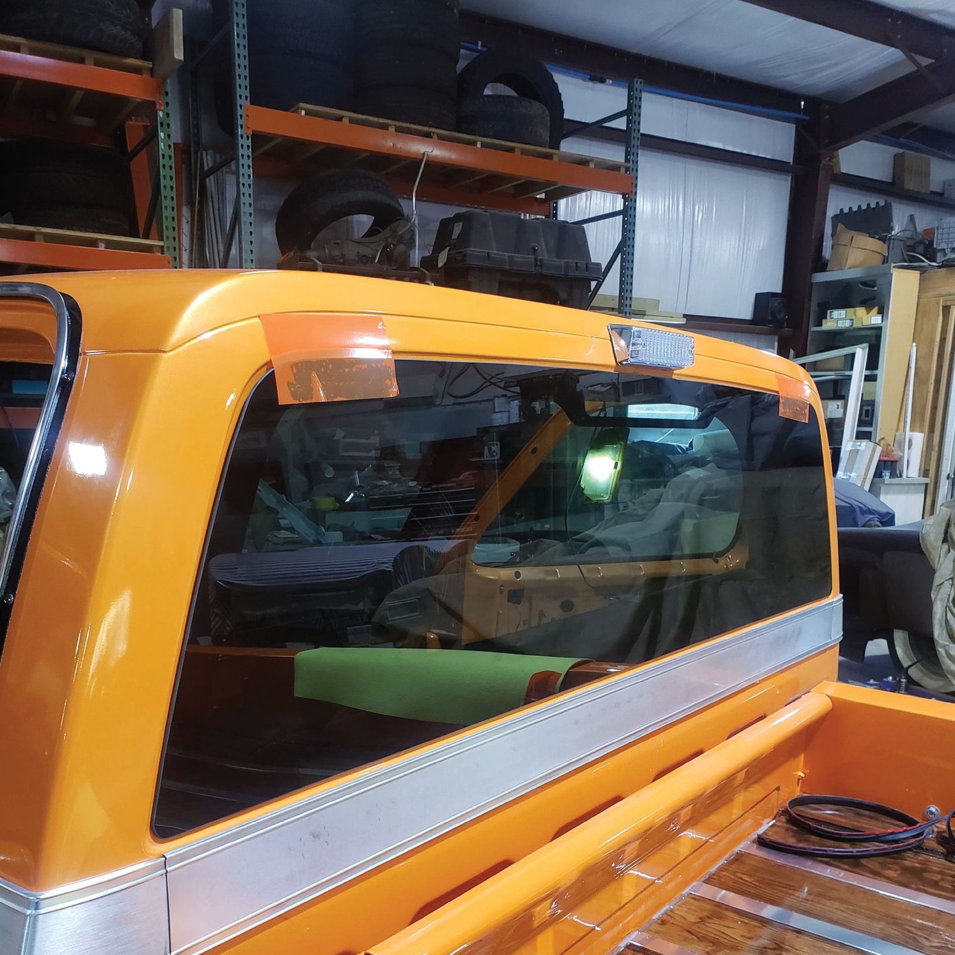 Orange and silver truck cab with rear window, inside a workshop.