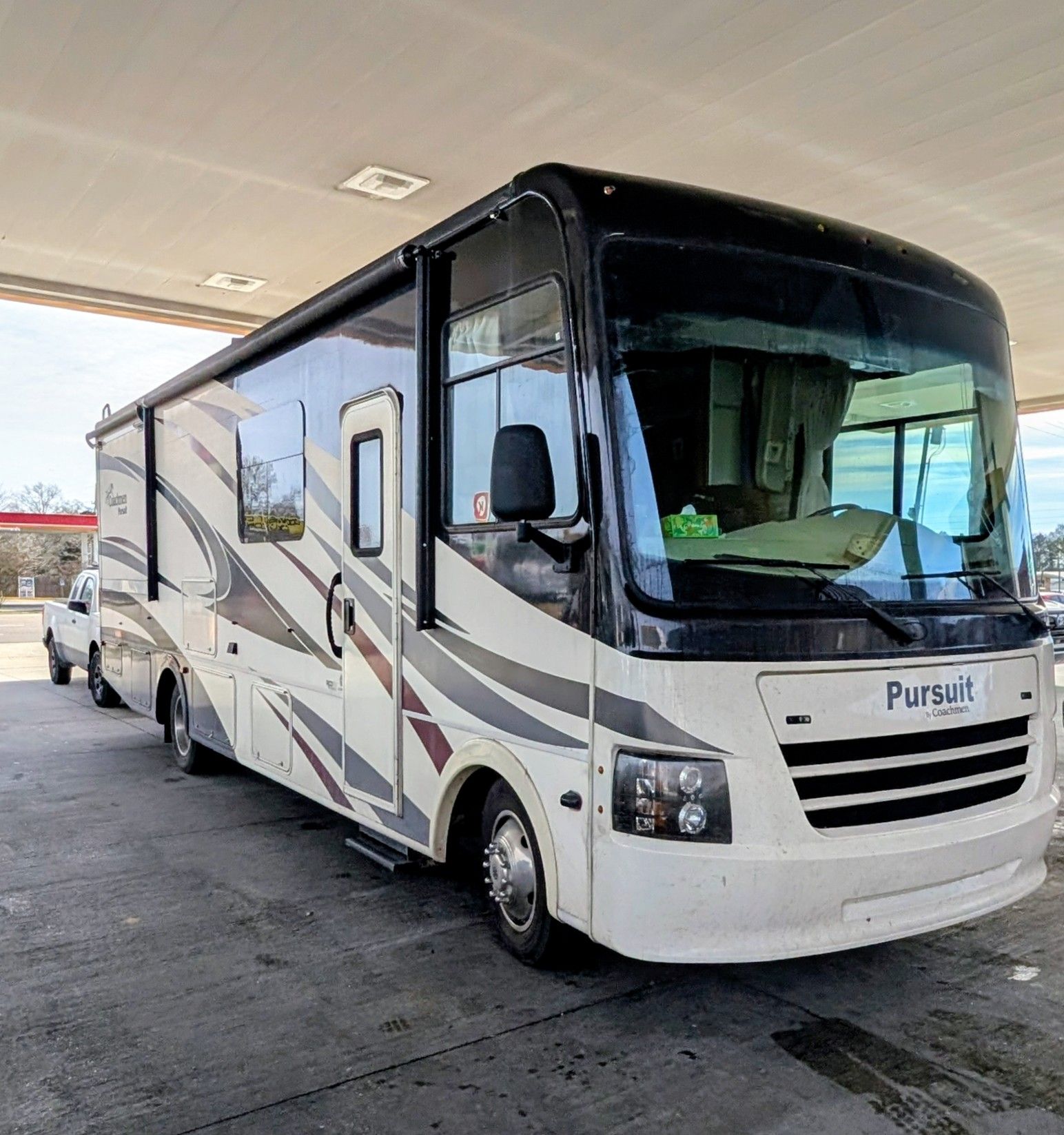 Black BMW sedan parked inside a garage; dirty wheels, light interior.
