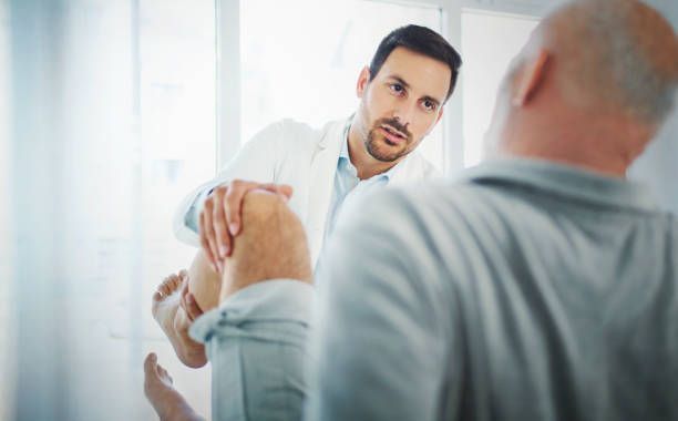 Doctor examining a patient's knee in a clinic setting.