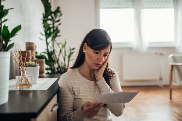 A worried woman reading an insurance denied claim at home.