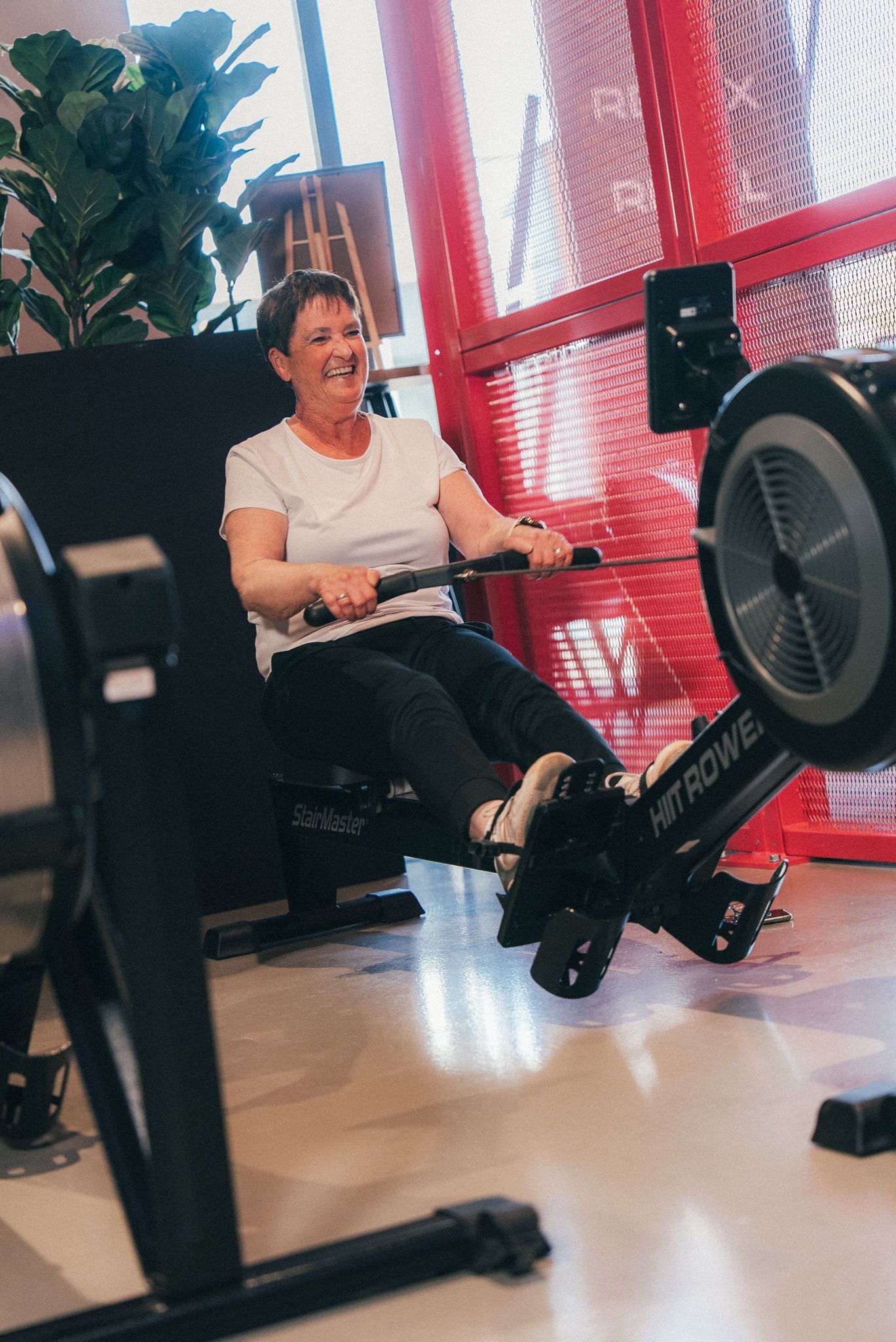 Een sportschool met veel fitnessapparatuur en een houten vloer.