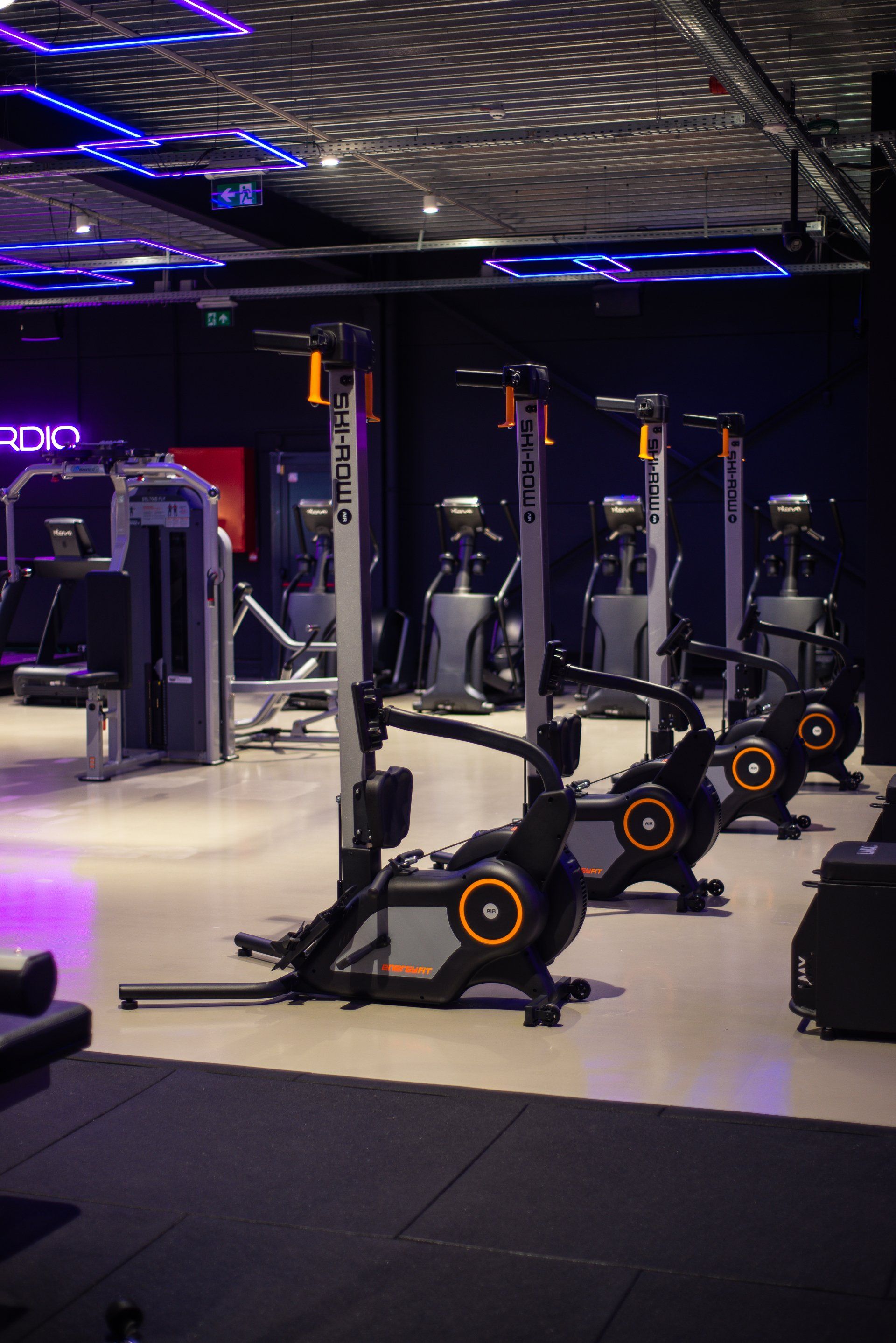 In een sportschool staat een rij hometrainers opgesteld.