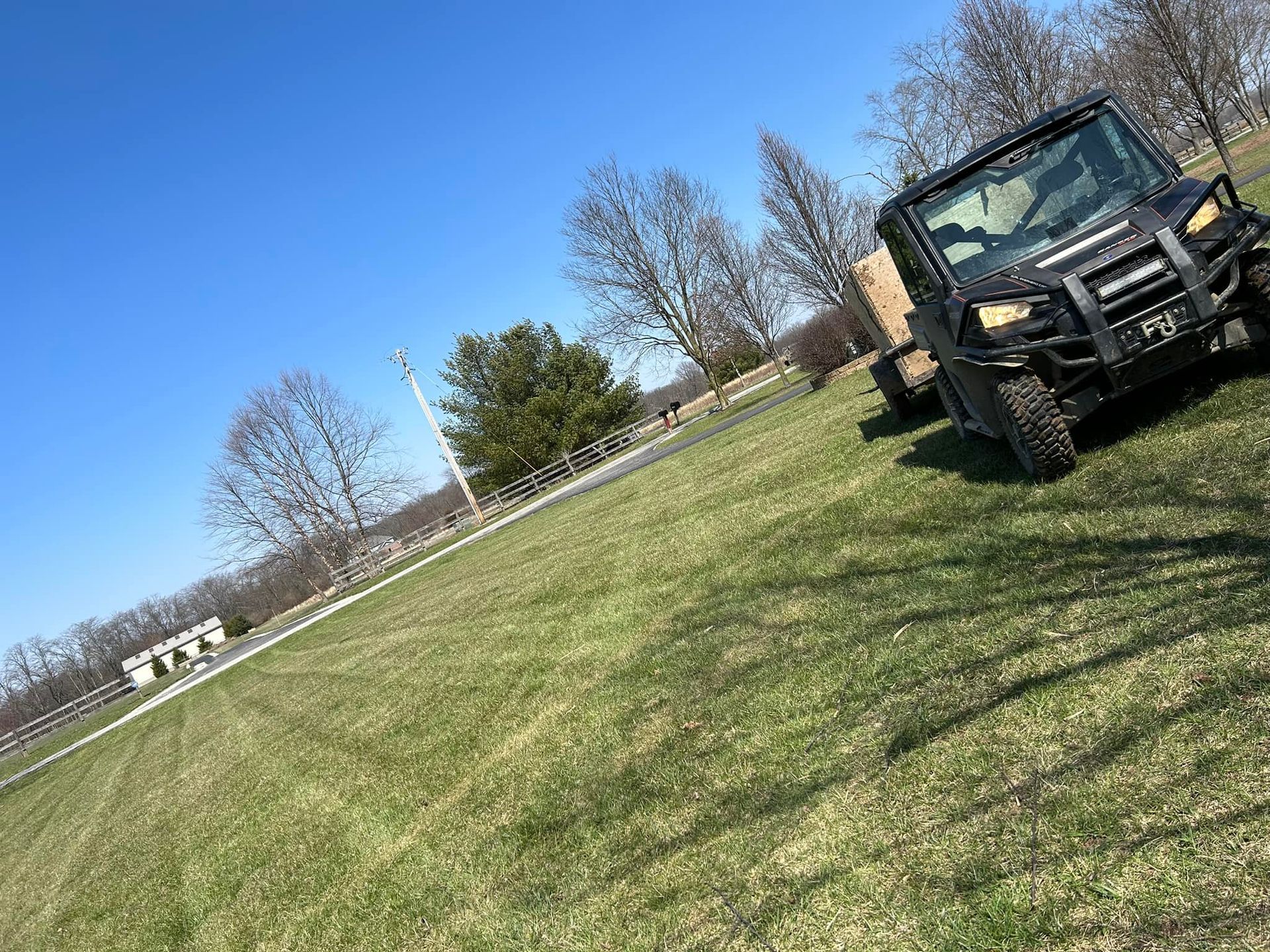 Black utility vehicle on a grassy hill; clear blue sky.