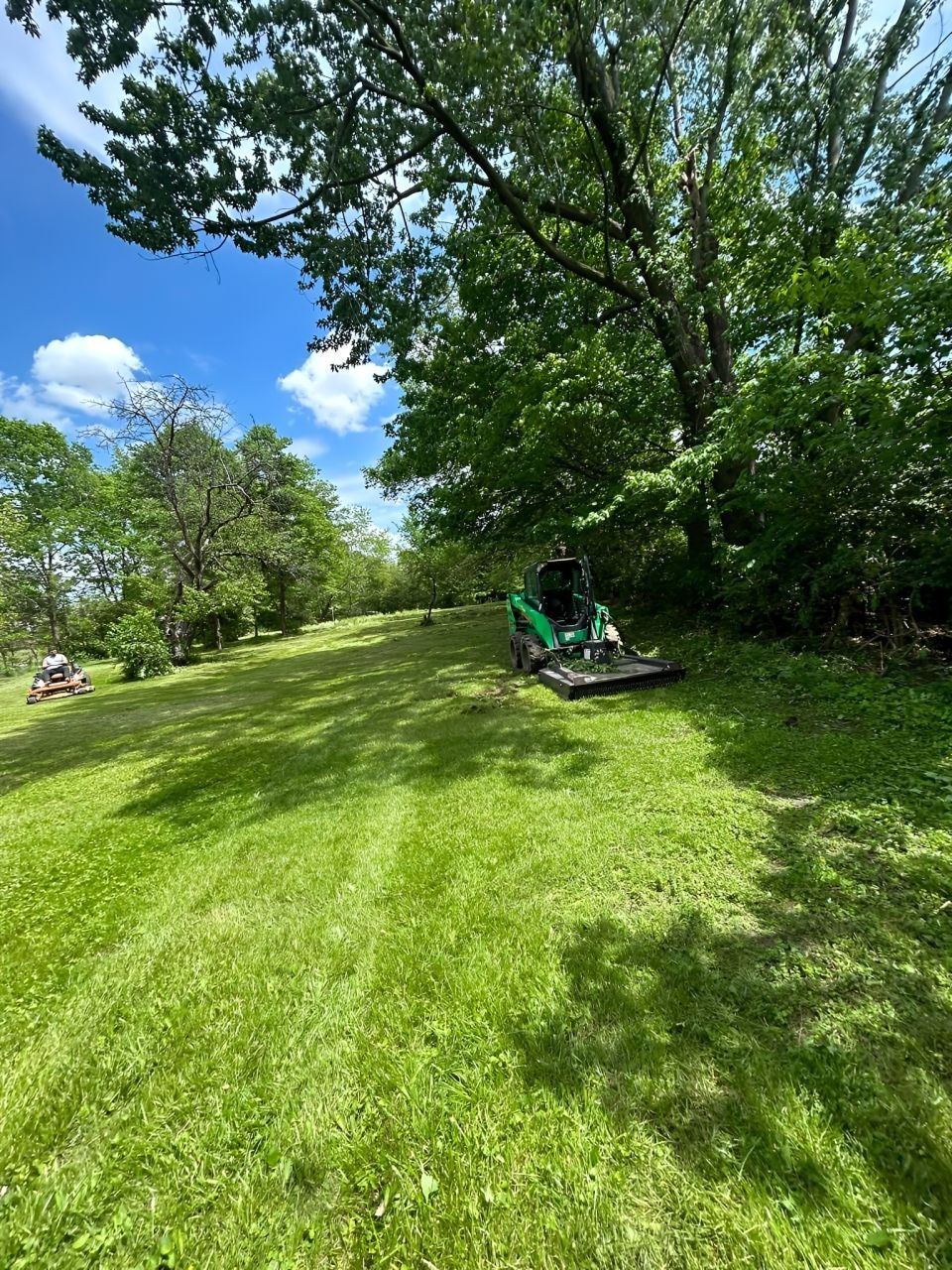 Orange and black zero-turn lawnmower on a green grassy lawn.