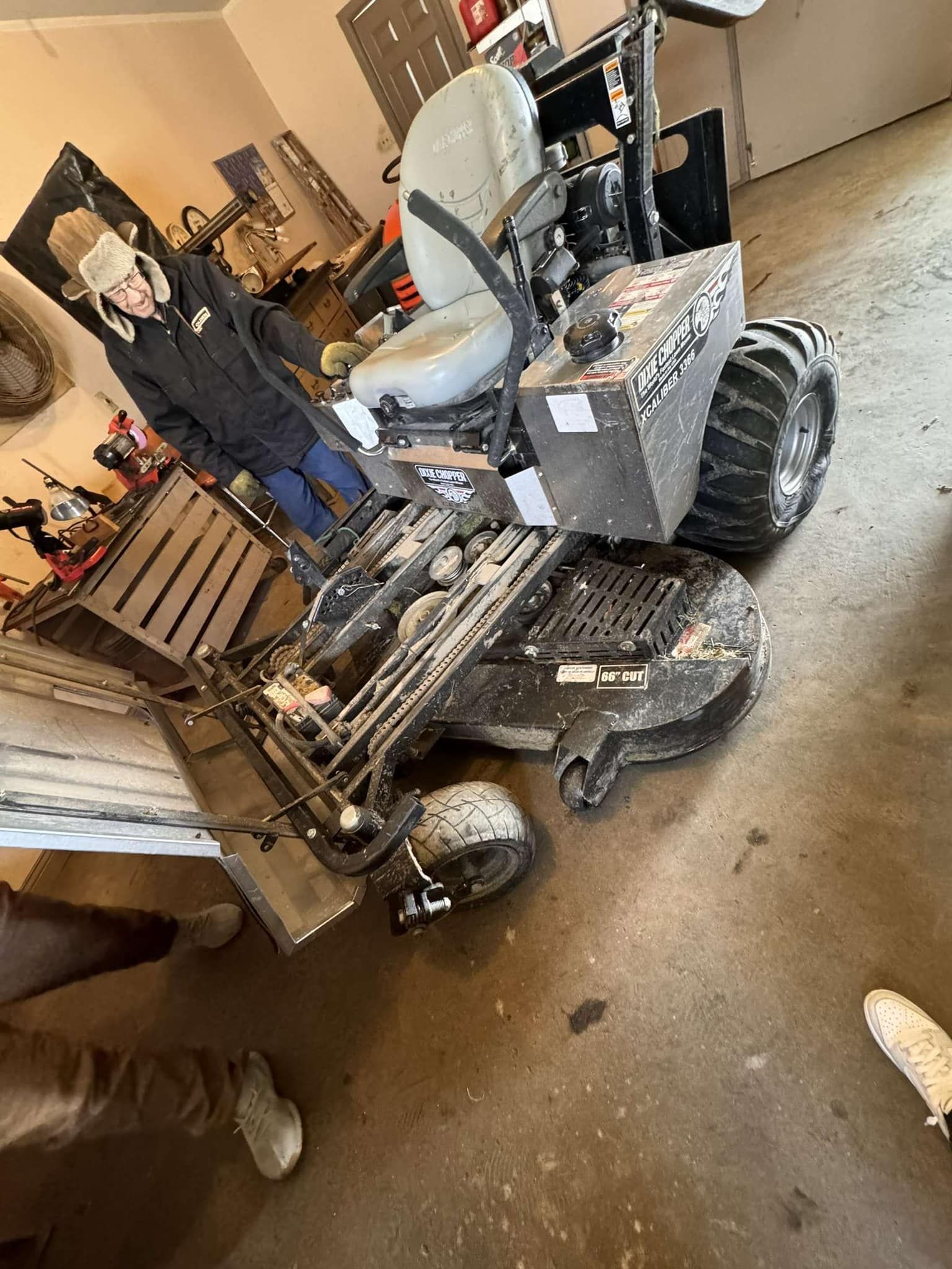 Person next to a snow-covered riding lawnmower in a garage.