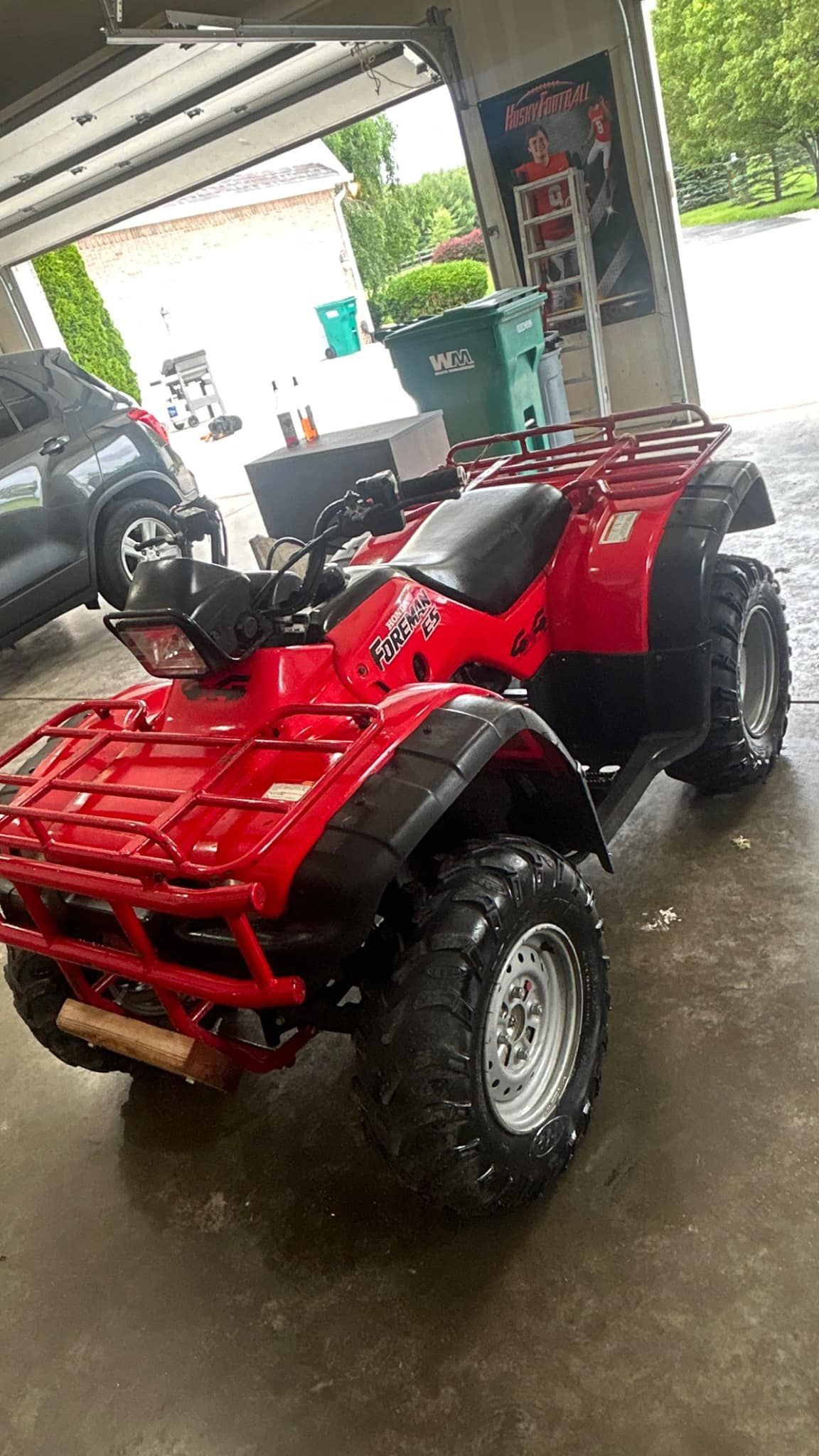Red ATV with luggage rack parked in a garage.