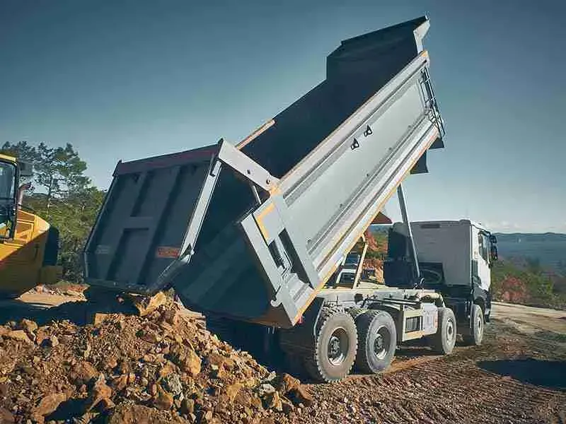 Dump truck unloading dirt on a construction site.