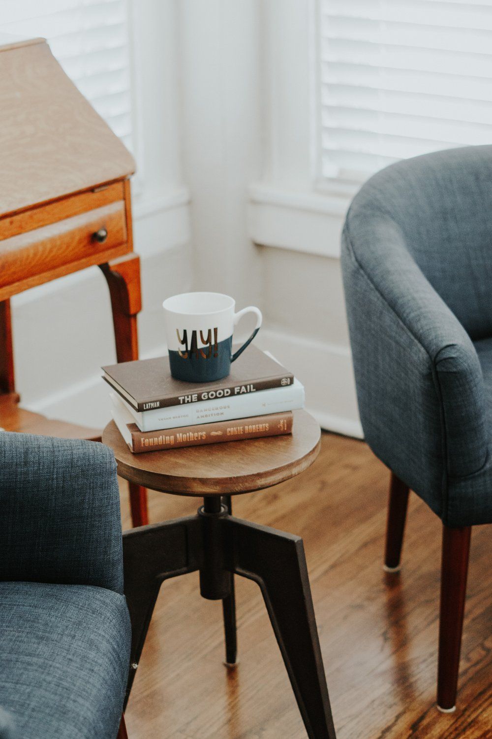 Two chairs and a table with a cup on top of a stack of books.