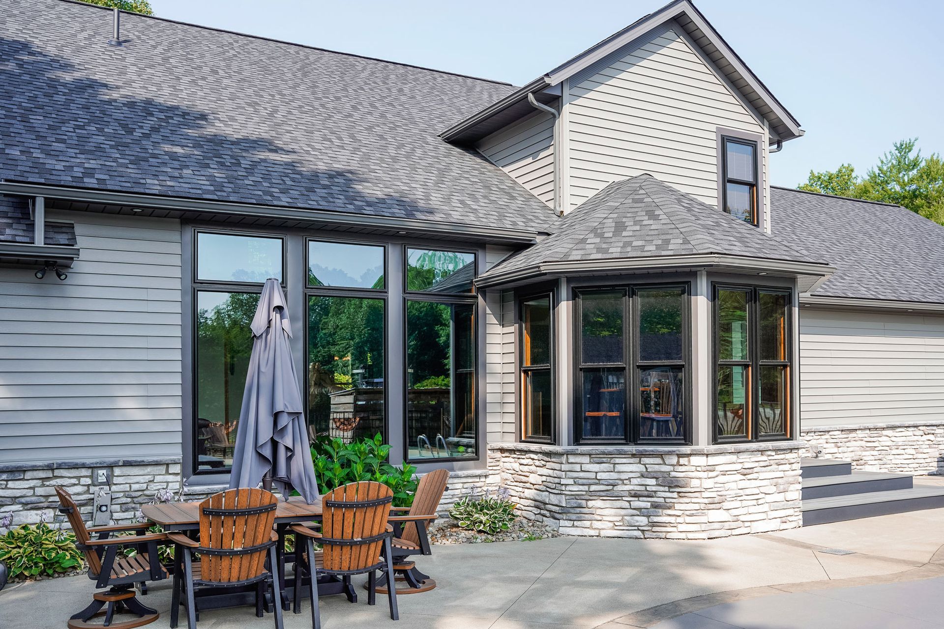 A large house with a patio area with a table and chairs and an umbrella.