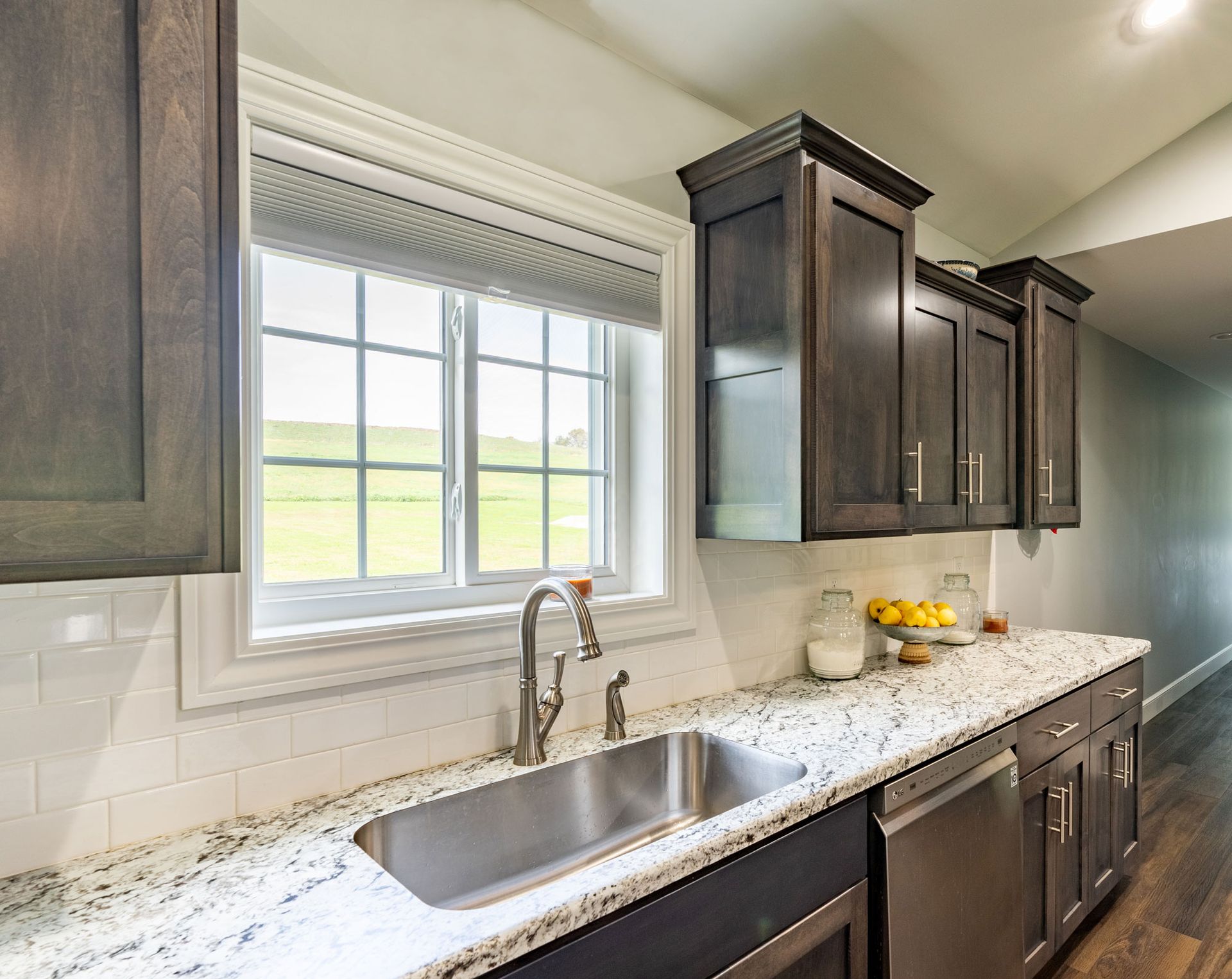 A kitchen with granite counter tops , stainless steel appliances , a sink and a window.