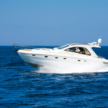 White motorboat speeding across blue water under a clear, blue sky.