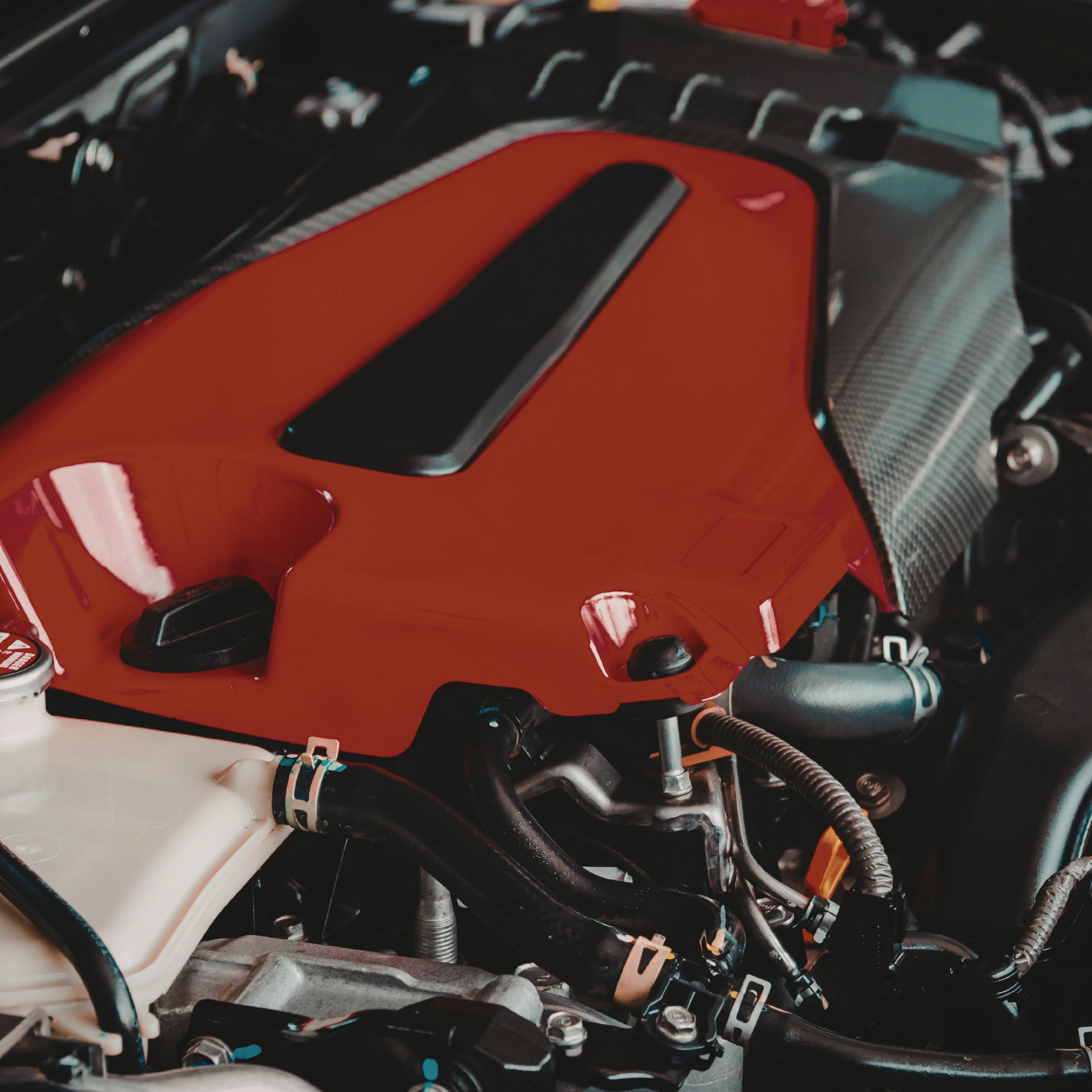 Red car engine cover, black accents, and various engine components.