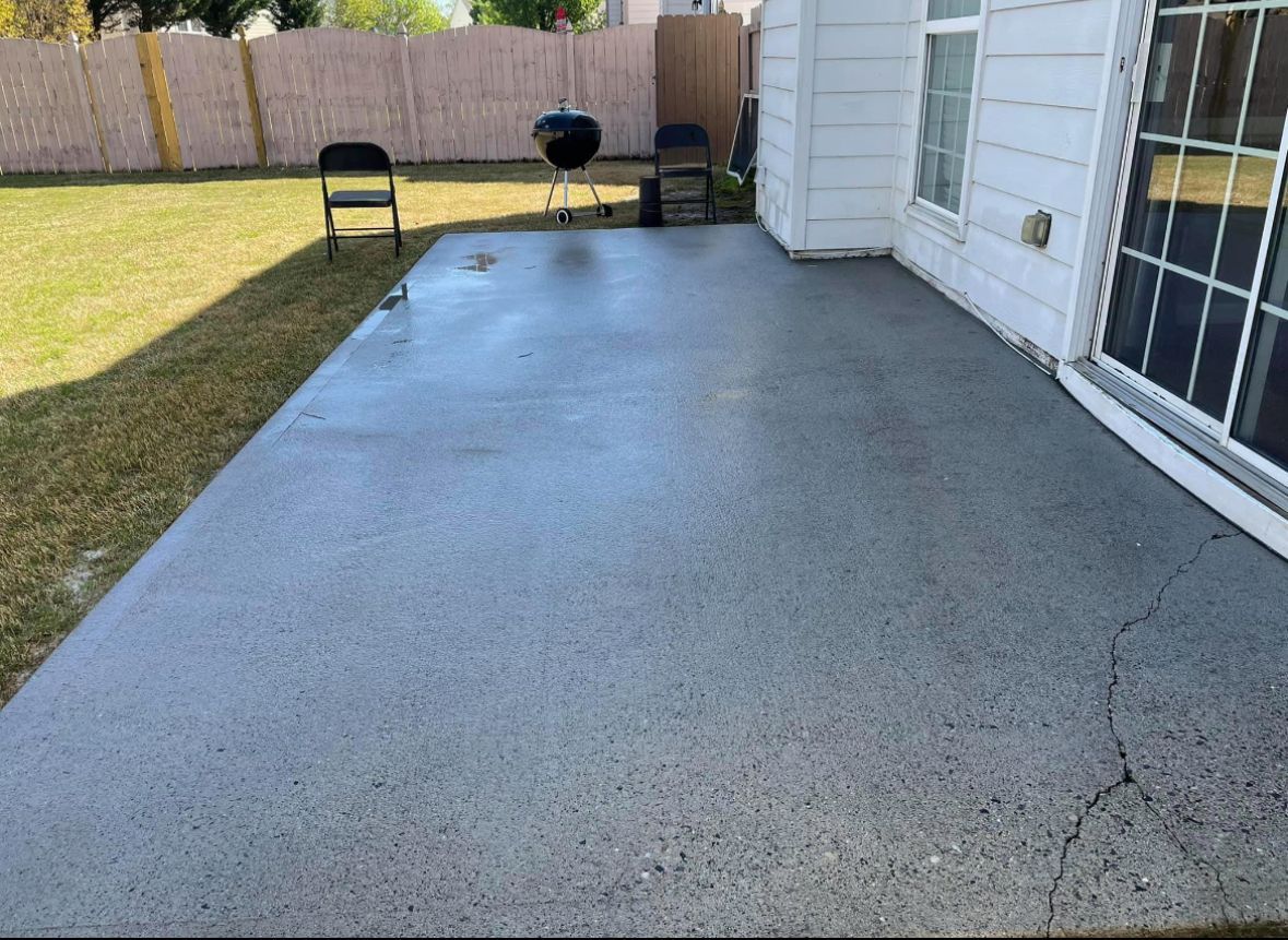 Concrete patio with two chairs, a grill, and a sliding door.