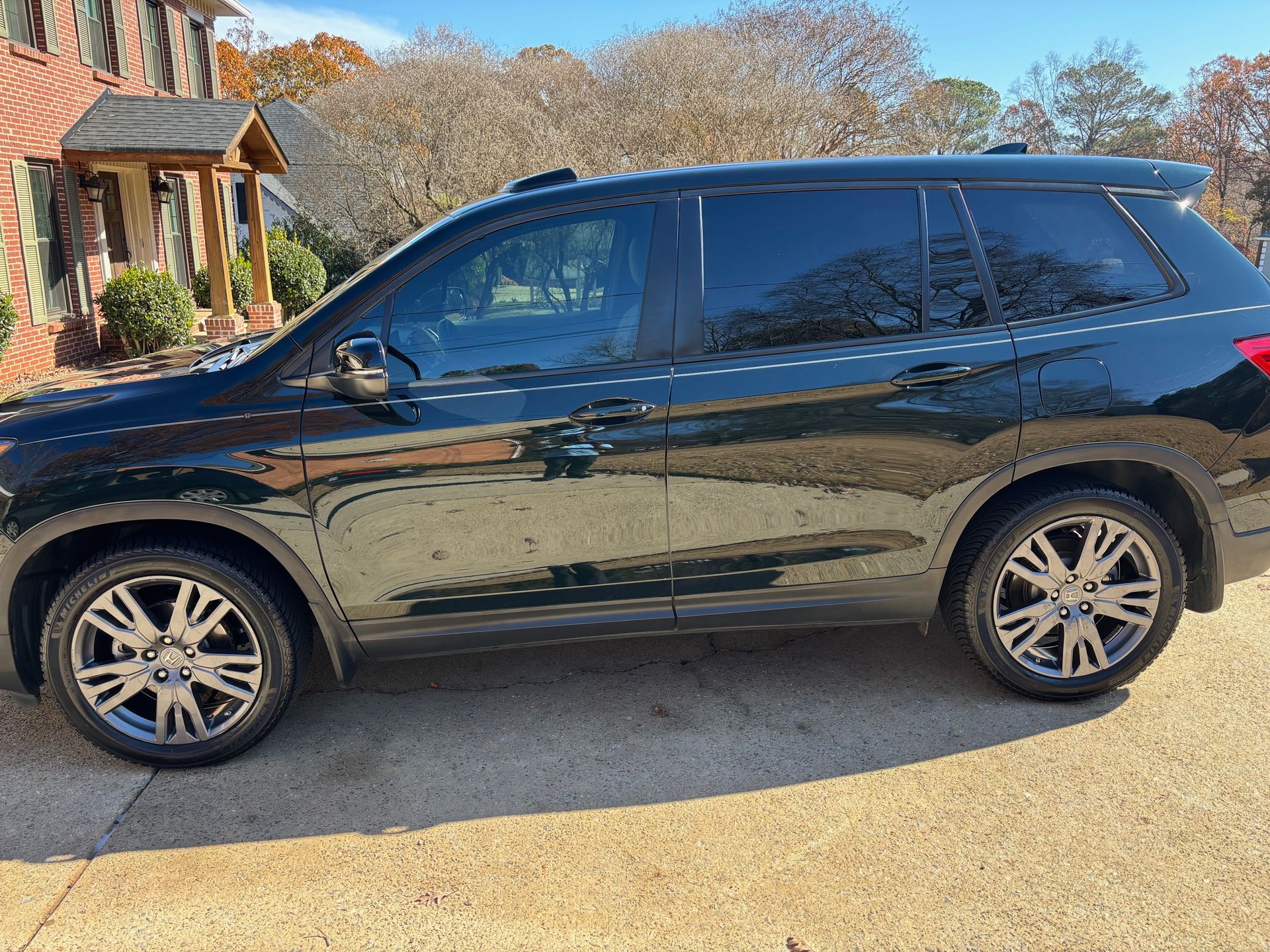 Dark SUV parked on a concrete driveway near a house on a sunny day.