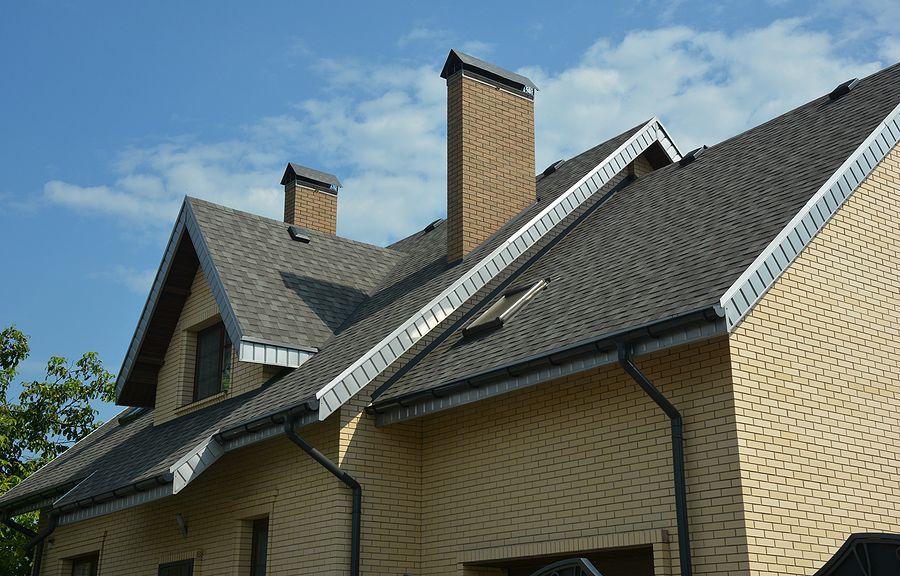 A brick house with a gray roof and chimneys.