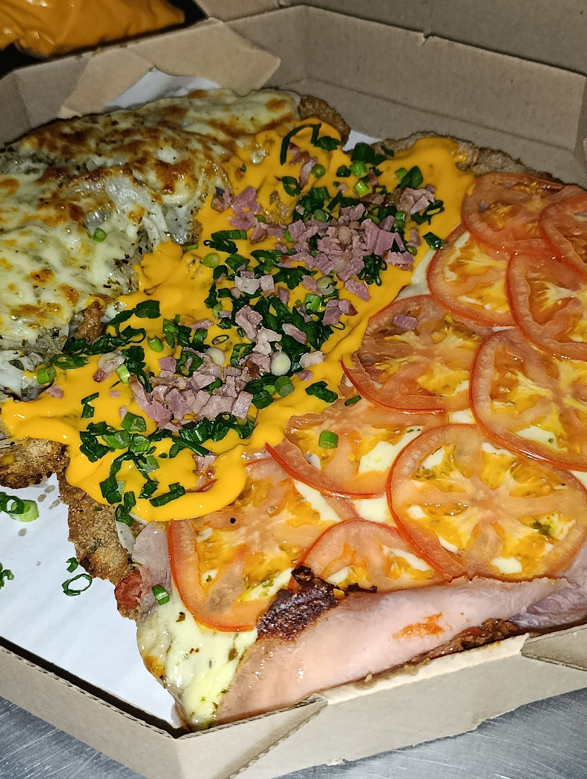 Porción de pizza con distintos ingredientes, incluidos tomates, jamón, queso y cebollas verdes.