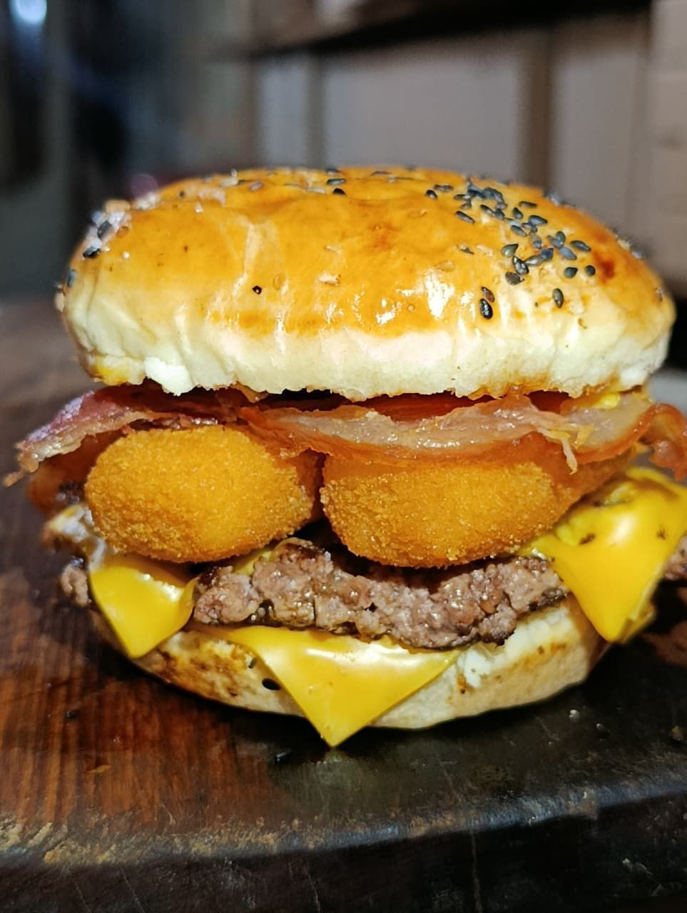 Deliciosa hamburguesa con hamburguesa, queso, tocino, aros de cebolla y pan con semillas de sésamo.