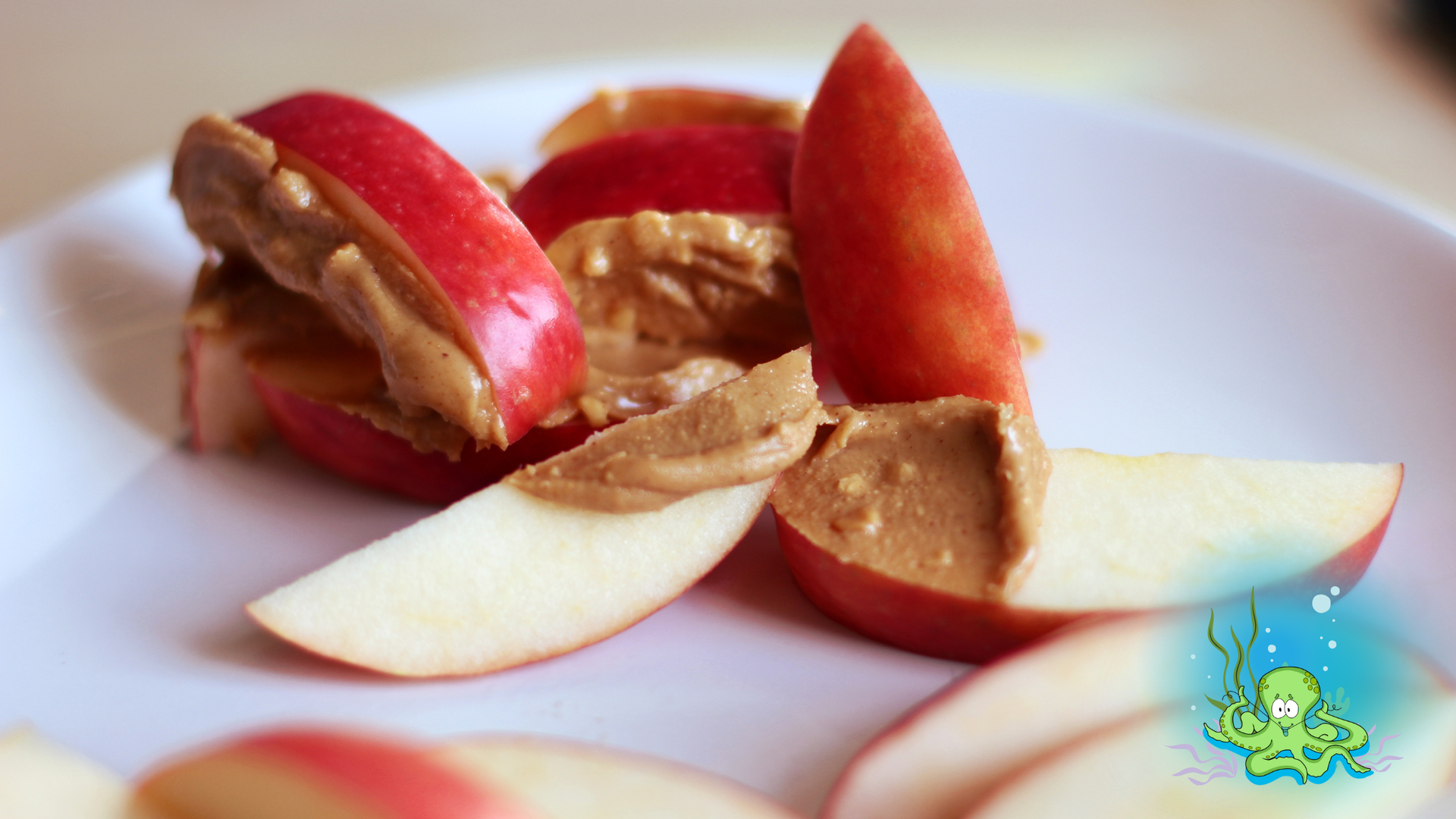 Apple slices with peanut butter on a white plate.