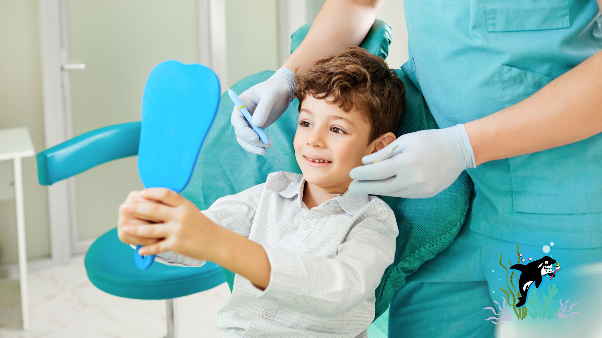 Boy smiles in dentist chair, holding mirror, dentist in teal scrubs.