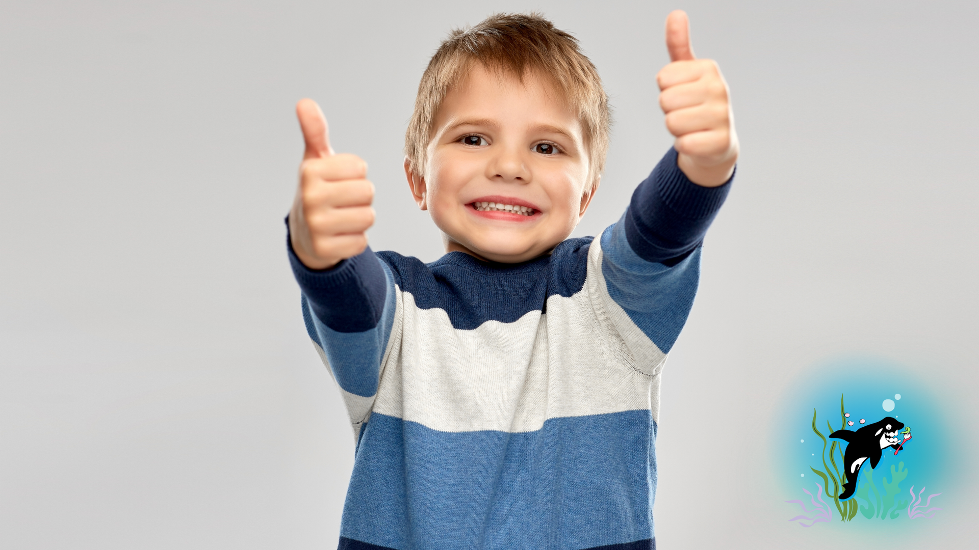 Smiling child with blue and white sweater gives two thumbs up.
