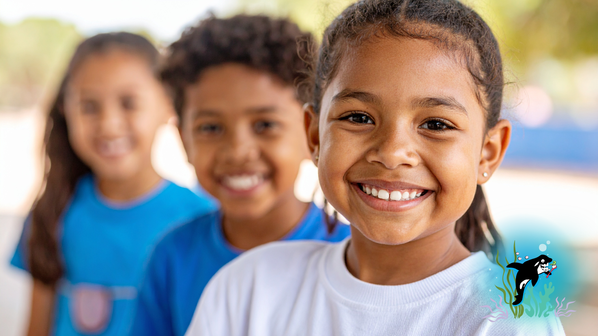 Three smiling children in blue and white shirts.