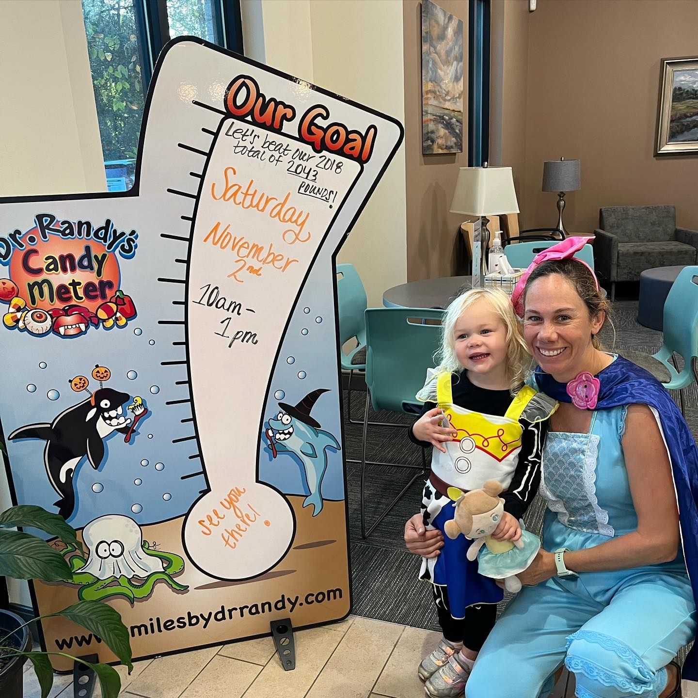 A woman is holding a little girl in front of a sign that says our goal