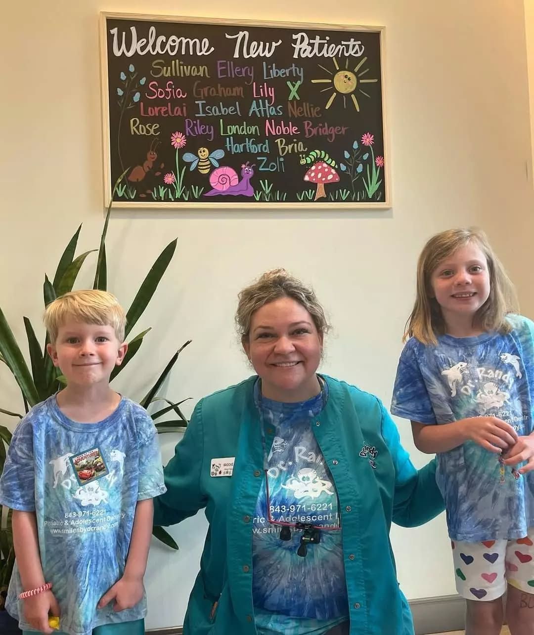 A woman and two children are posing for a picture in front of a welcome sign.