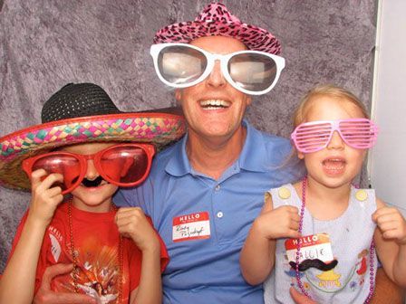 A man and two children are posing for a picture in a photo booth.