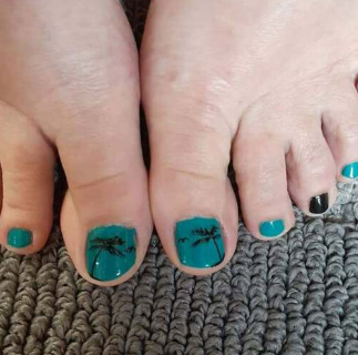 A close up of a person 's feet with blue nails and a palm tree design.