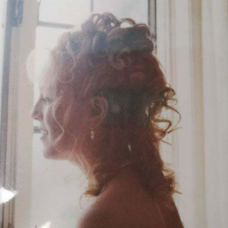 A woman with red hair is standing in front of a window.