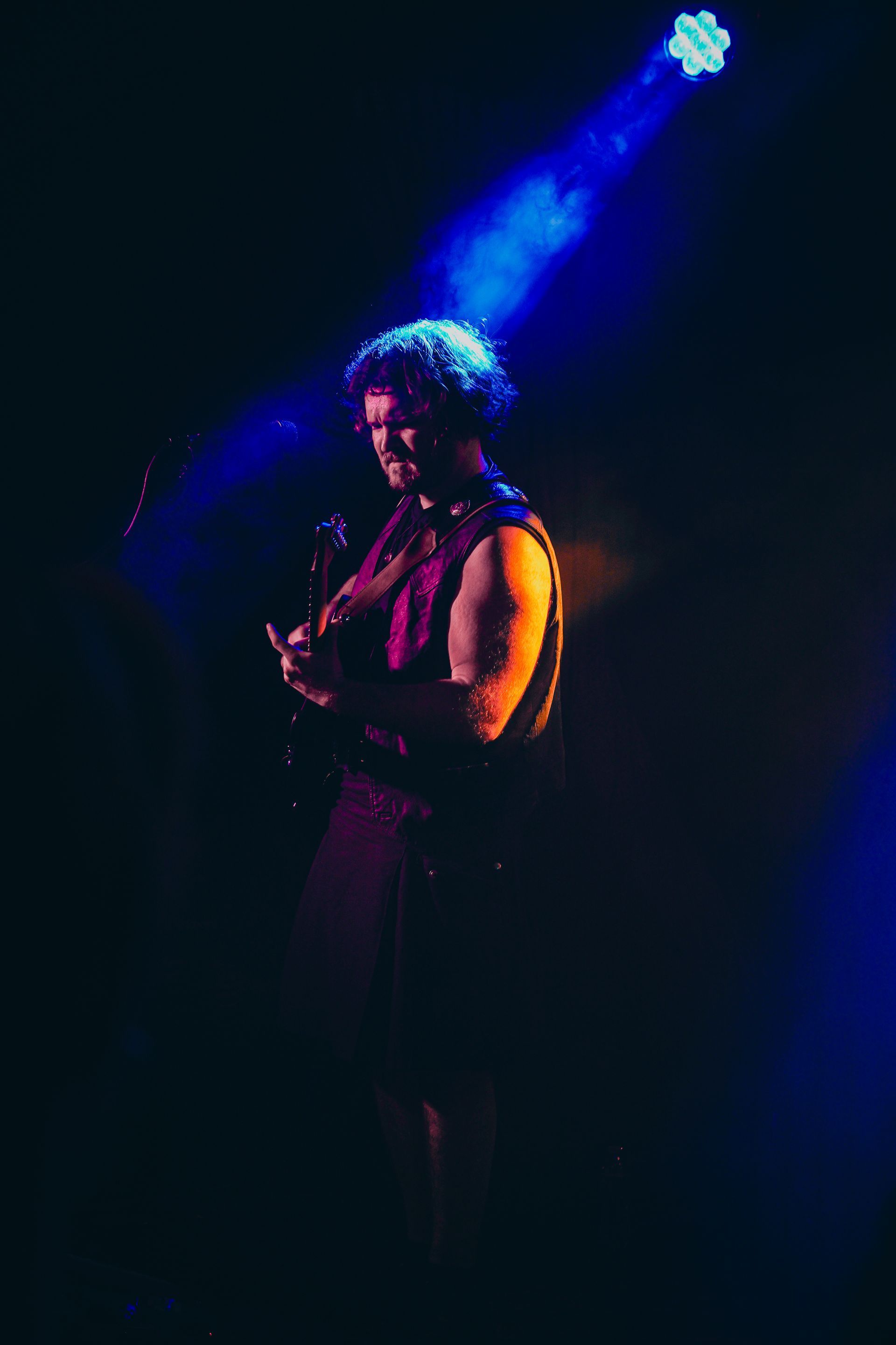 A man is playing a guitar and singing into a microphone on a stage.