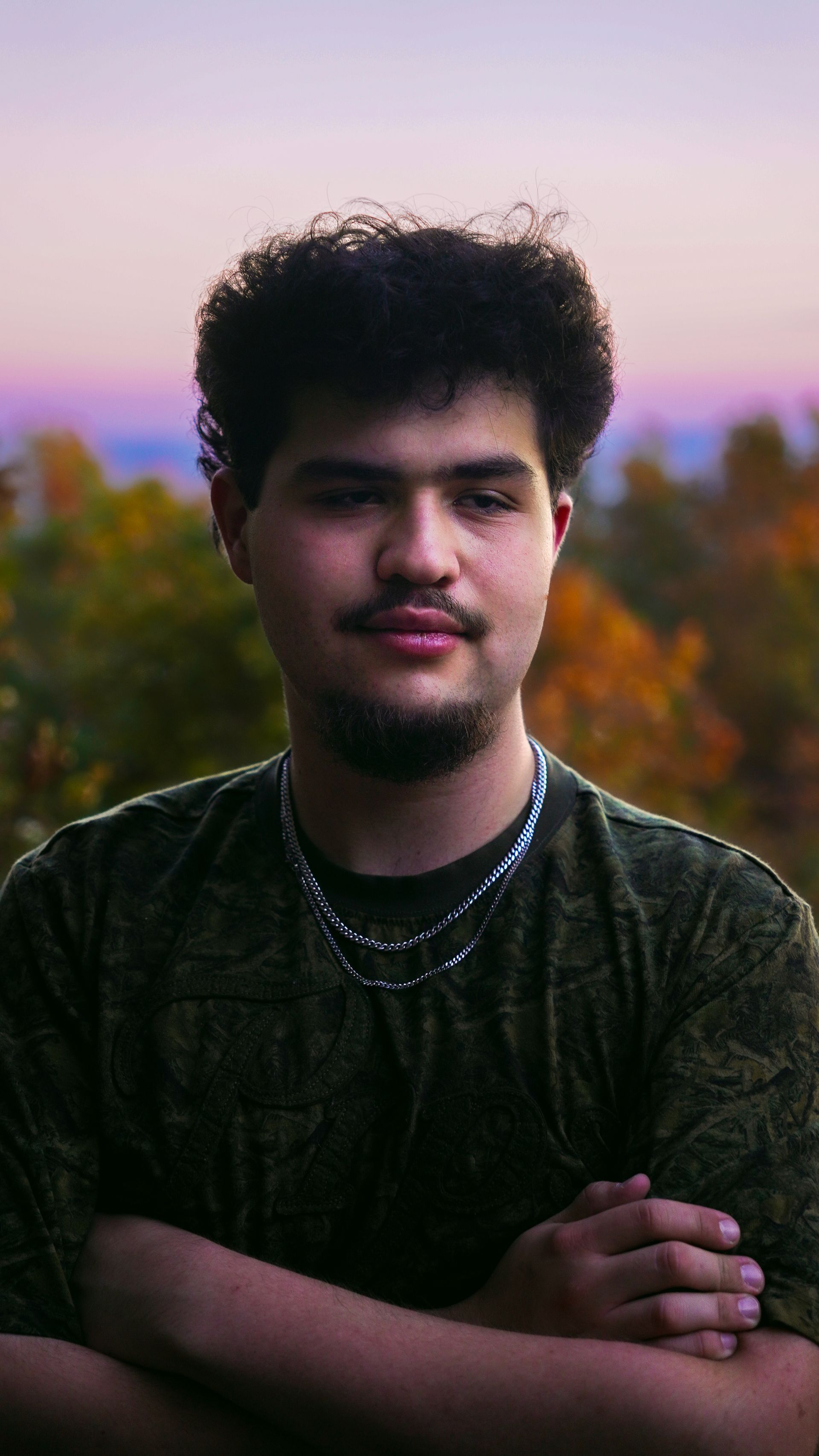 A man is squatting down while holding a camera and a microphone.