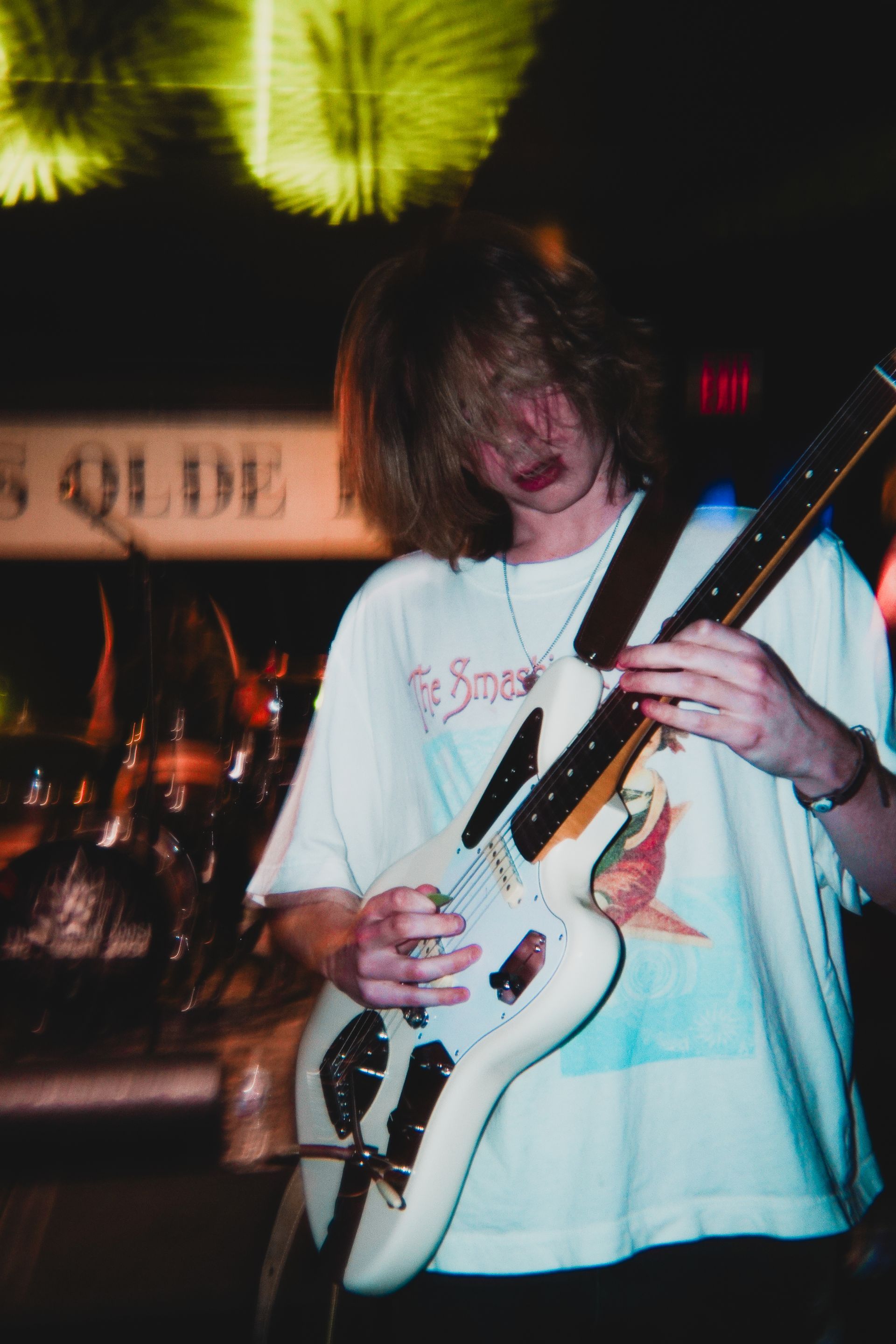 A man is playing a guitar in front of a sign that says exit