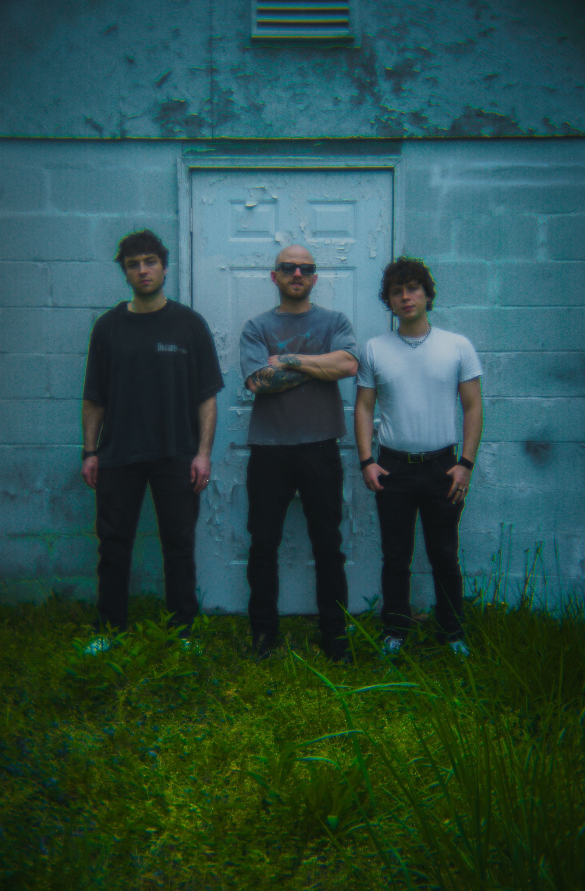 Three men are standing in front of a white door.