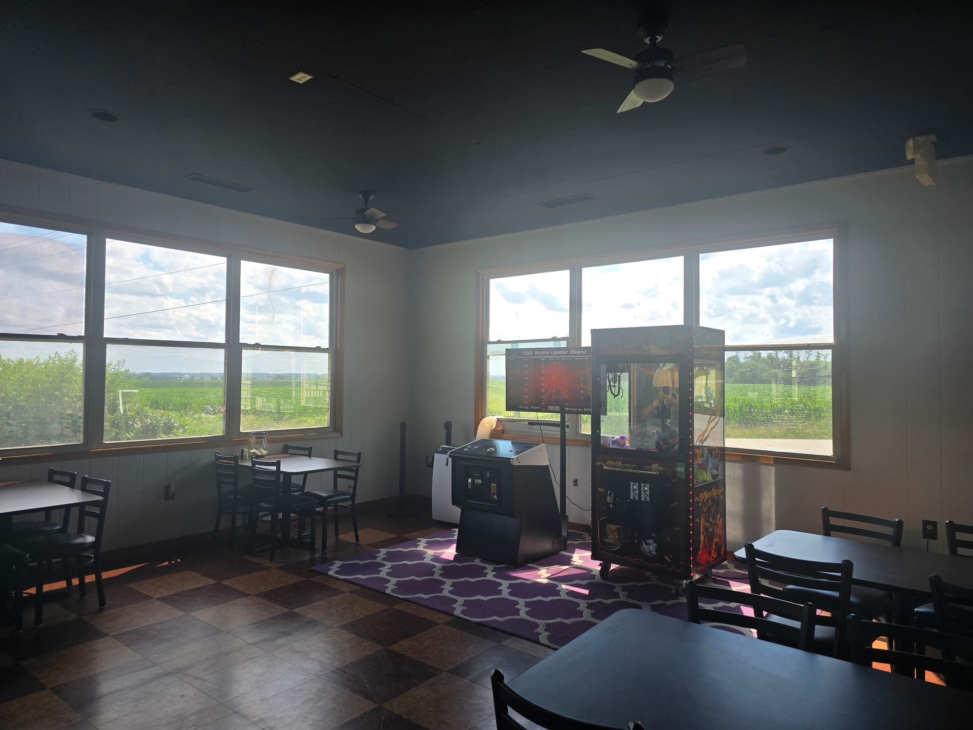 A restaurant with tables and chairs and a claw machine