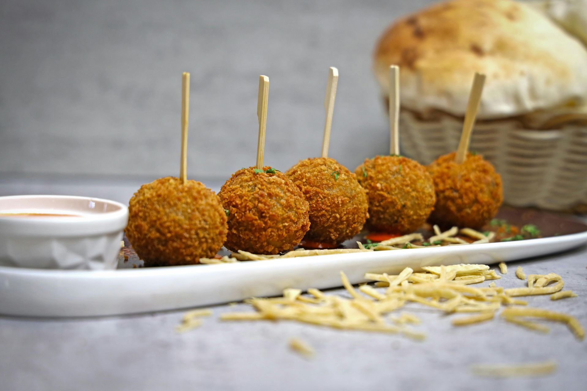 A white plate topped with fried food balls on sticks.