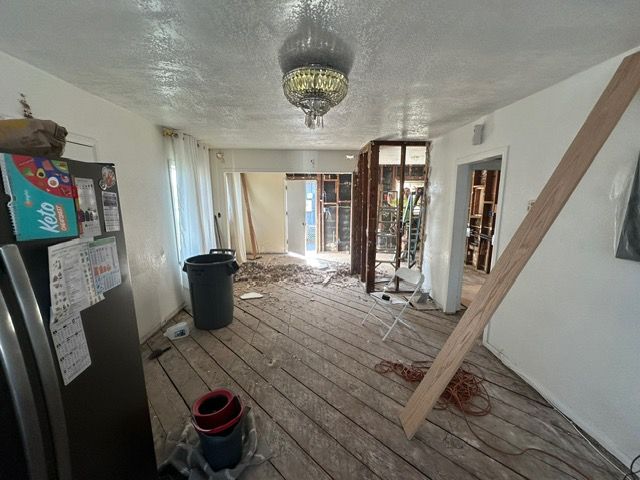 Night view of a brick house with landscape lighting. Two people stand on a lit path leading to the front door.