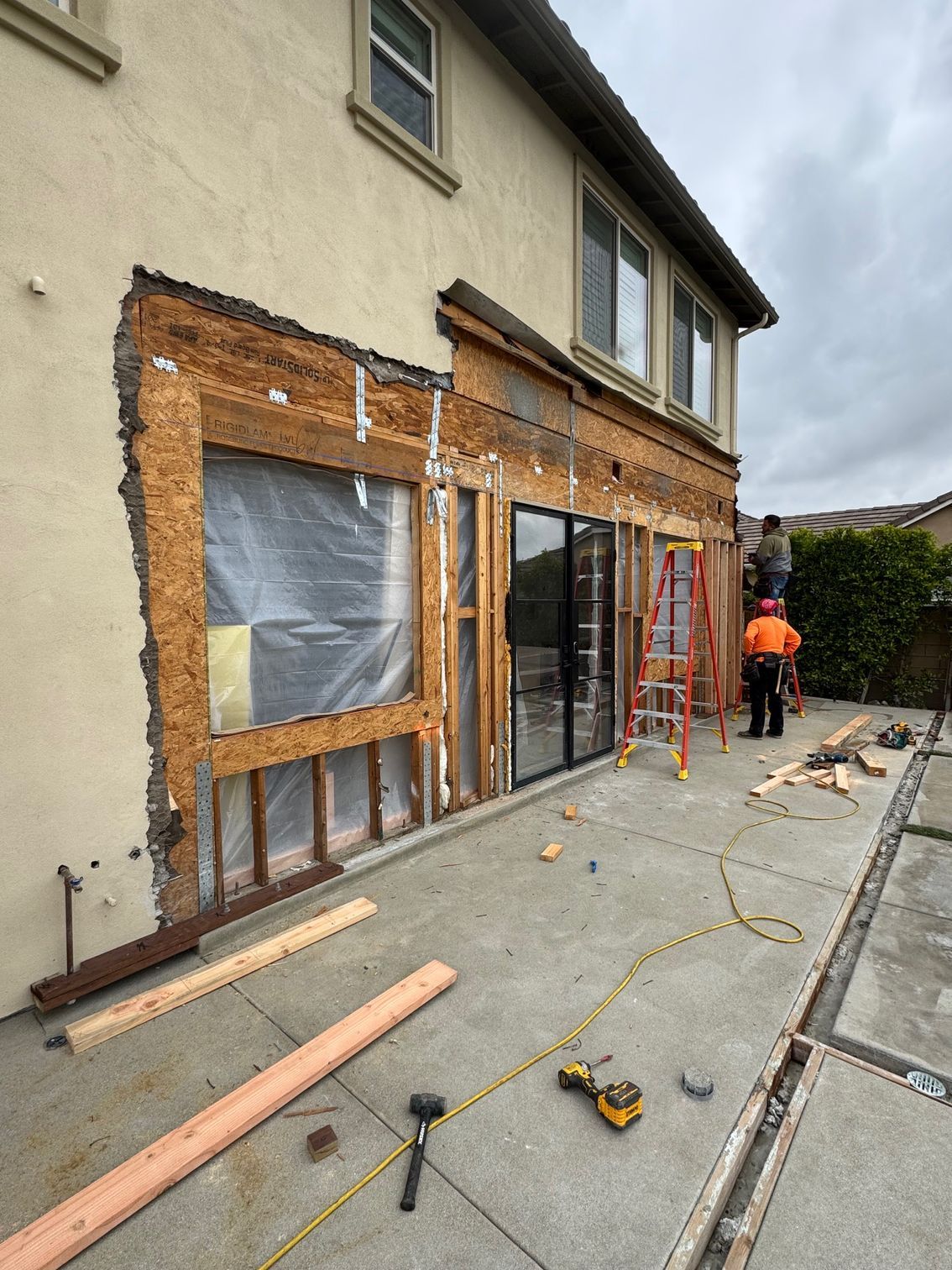 Construction site, workers on scaffolding, exterior wall of a two-story building being remodeled.