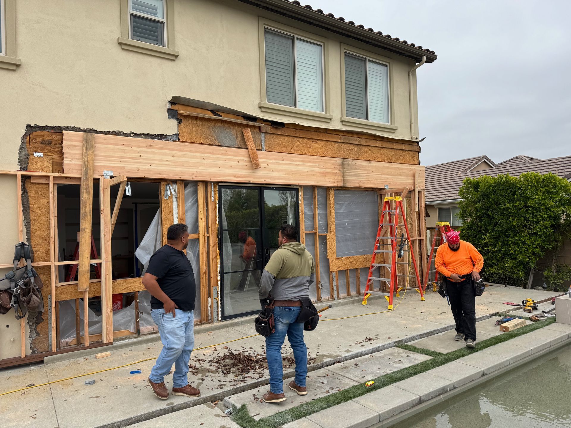 Construction workers building an addition onto a home near a pool.