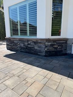 Stone facade base with light blue shutters and patio pavers.
