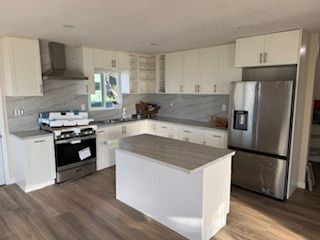 Modern white kitchen with stainless steel appliances and island.