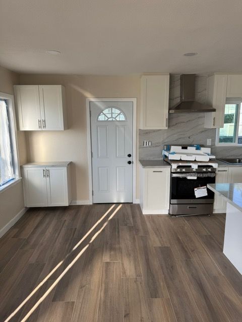Modern kitchen with white cabinets, stainless steel appliances, and wood-look flooring.