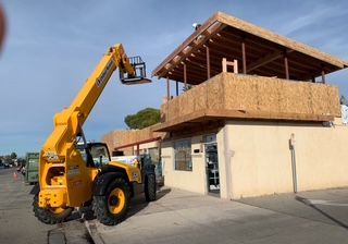 Yellow forklift at building construction site, lifting materials to upper level.