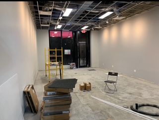 Empty room under construction with exposed ceiling, drywall, and scattered building materials.