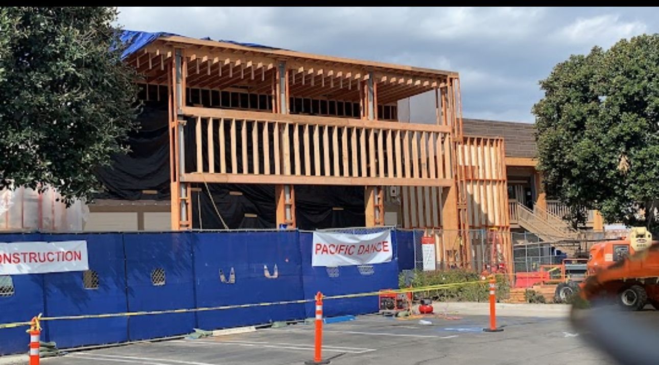 Electrician in blue shirt working on an electrical panel in a wooden-framed wall.