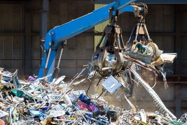 A crane is picking up a pile of scrap metal.