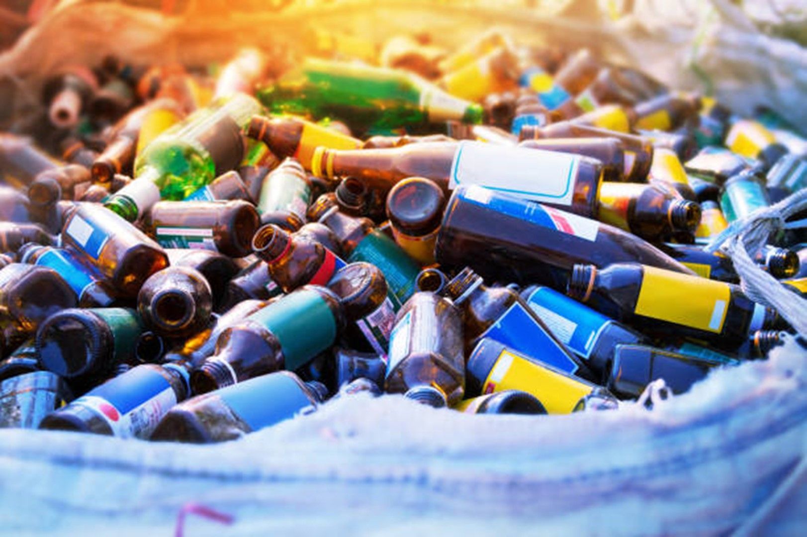 A pile of empty glass bottles in a bag.