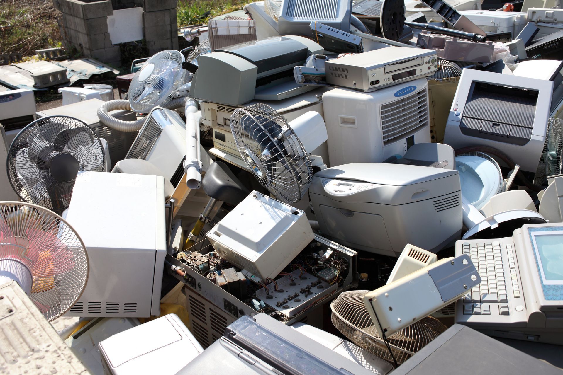 A pile of old electronics including printers and fans